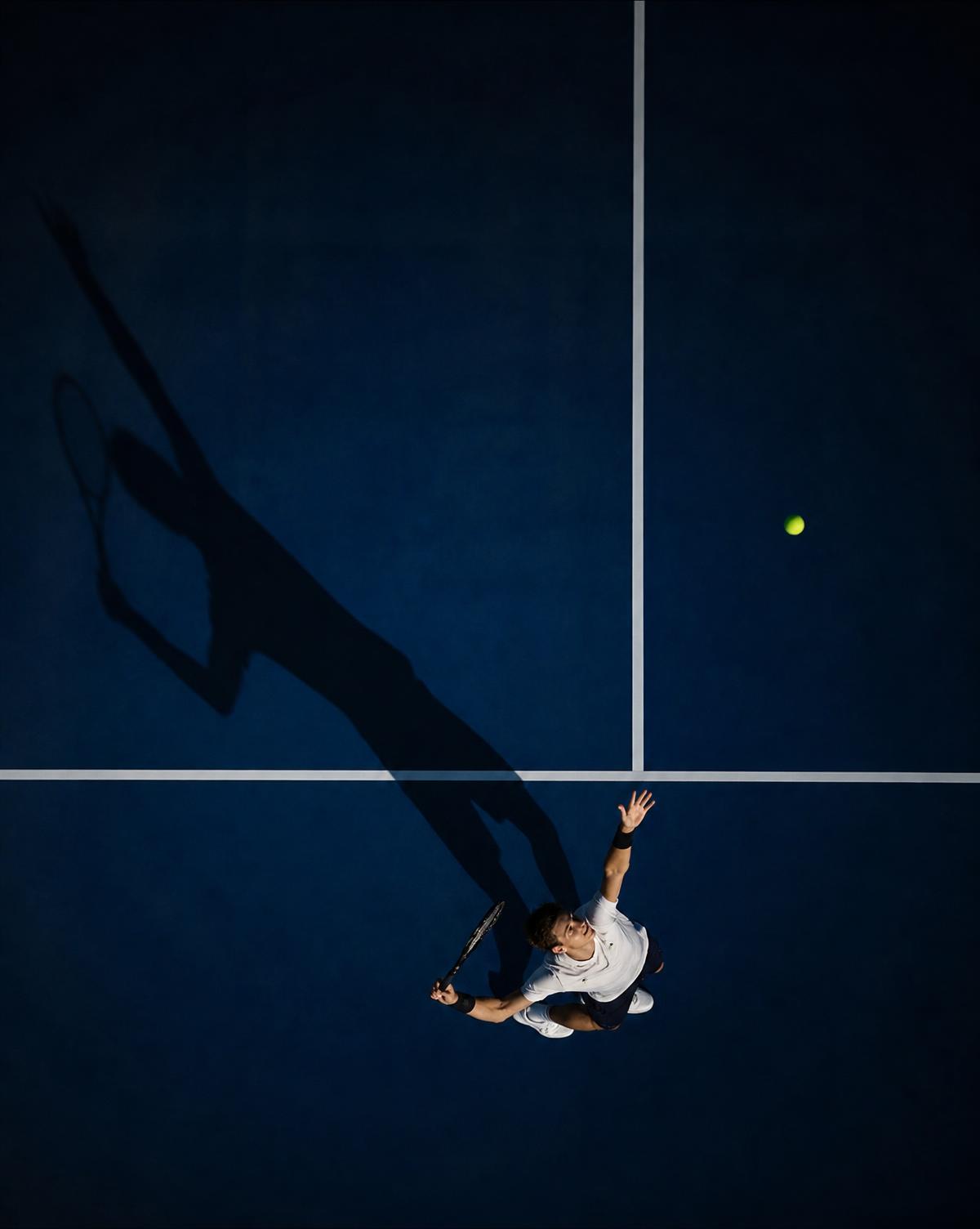 Overhead view of a tennis player serving on a dark court